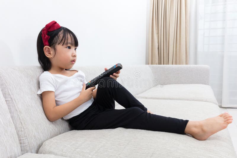 Niña china asiática que sostiene una TV teledirigida foto de archivo Niña china asiática que sostiene una TV teledirigida foto de archivo