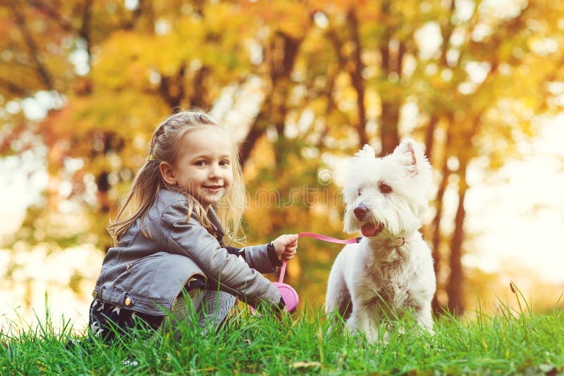 Niña con el perro en parque del otoño Muchacha sonriente linda que se divierte en caminar con su animal doméstico Niño feliz que fotografía de archivo Niña con el perro en parque del otoño Muchacha sonriente linda que se divierte en caminar con su animal doméstico Niño feliz que fotografía de archivo