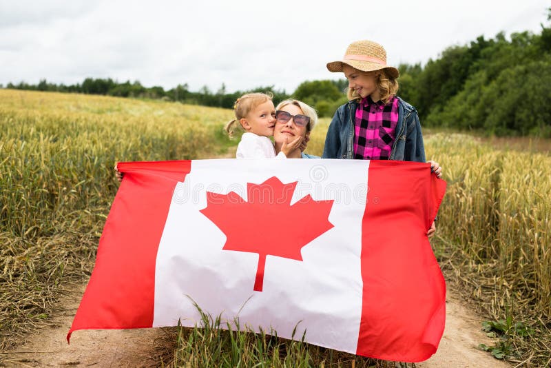 Niña con niños en el campo de juego con bandera canadiense foto de archivo