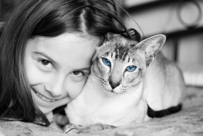 A cute little girl snuggling up to her Siamese cat. A cute little girl snuggling up to her Siamese cat.