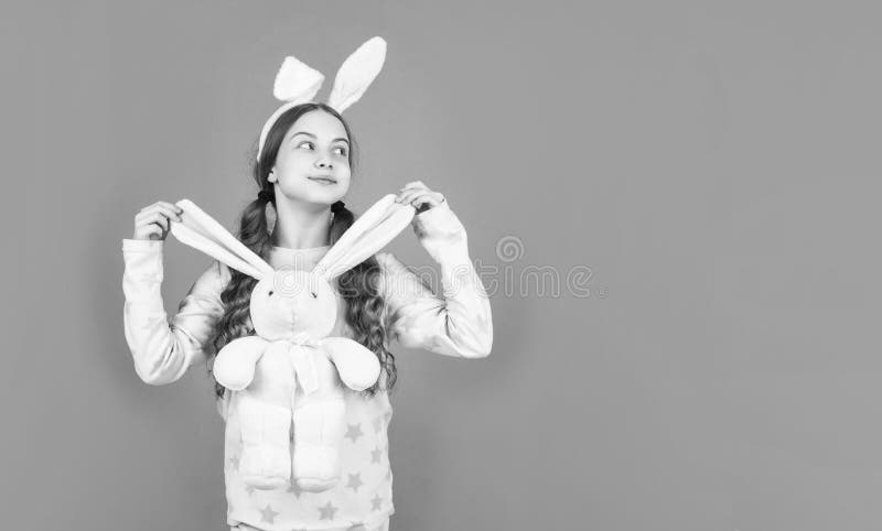 Niña de Pascua feliz en orejas de conejo conejo y pijamas jugando con espacio de juguete en Pascua imagen de archivo