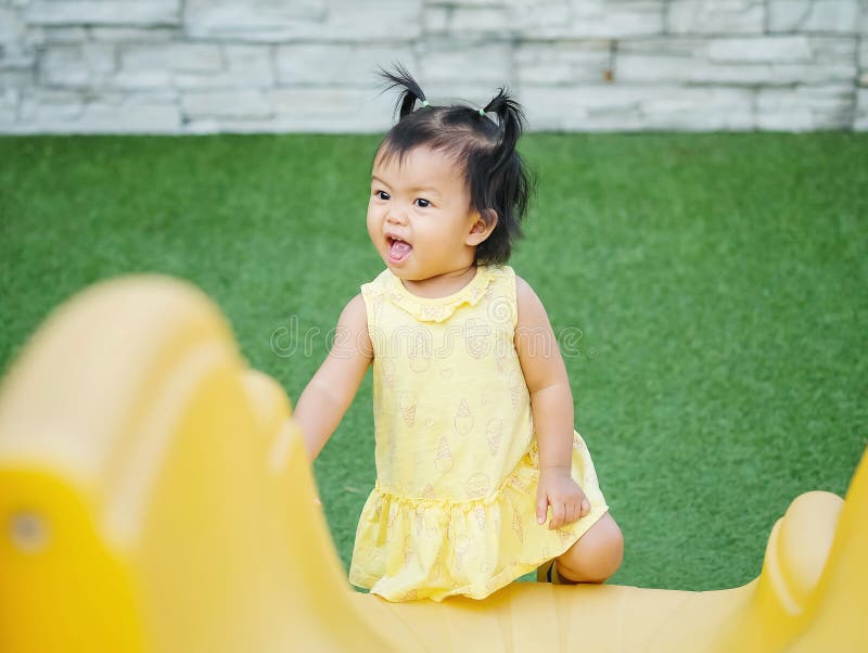 Niña del primer con el movimiento divertido cuando ella juega un resbalador en el fondo del patio imágenes de archivo libres de regalías