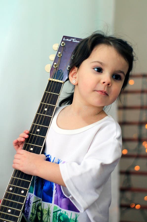 niña divertida en la camiseta que sostiene una guitarra foto de archivo libre de regalías niña divertida en la camiseta que sostiene una guitarra foto de archivo libre de regalías