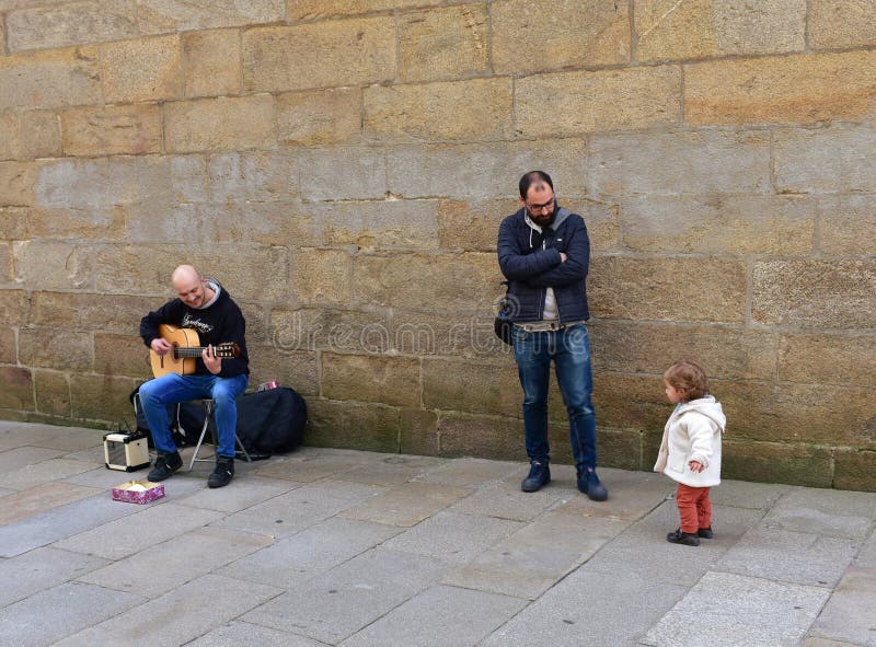 Niña divertida y hombre que tocan la guitarra en una calle cerca de la catedral Santiago de Compostela, España, el 22 de febrero imagen de archivo libre de regalías Niña divertida y hombre que tocan la guitarra en una calle cerca de la catedral Santiago de Compostela, España, el 22 de febrero imagen de archivo libre de regalías