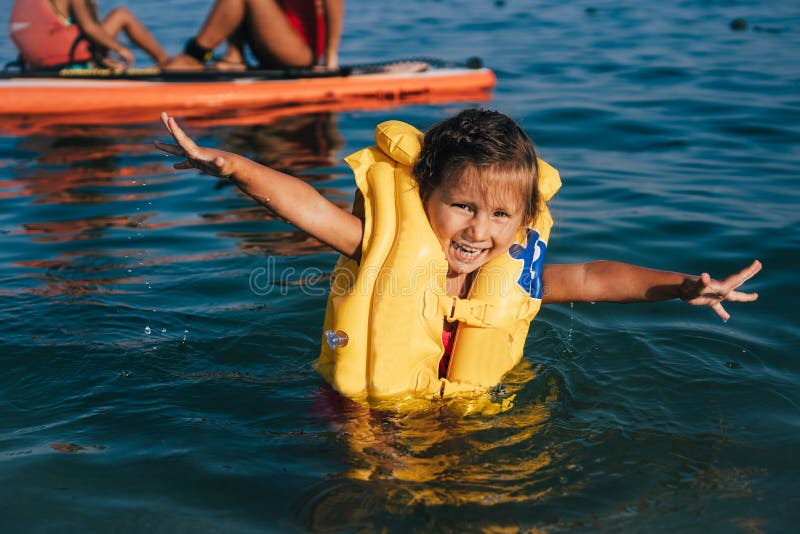 Niña en un chaleco salvavidas bañarse en el mar imagen de archivo libre de regalías Niña en un chaleco salvavidas bañarse en el mar imagen de archivo libre de regalías
