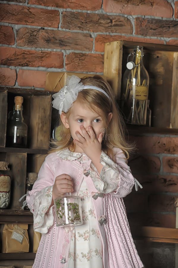 Niña en un vestido rosado que se sienta en cocina retra fotografía de archivo libre de regalías Niña en un vestido rosado que se sienta en cocina retra fotografía de archivo libre de regalías