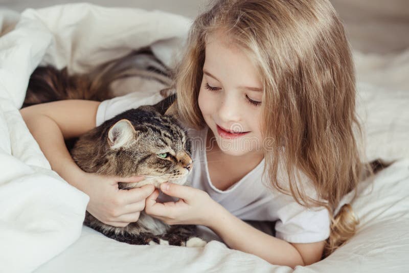 Charming little girl hugging her cat lying in bed. Charming little girl hugging her cat lying in bed