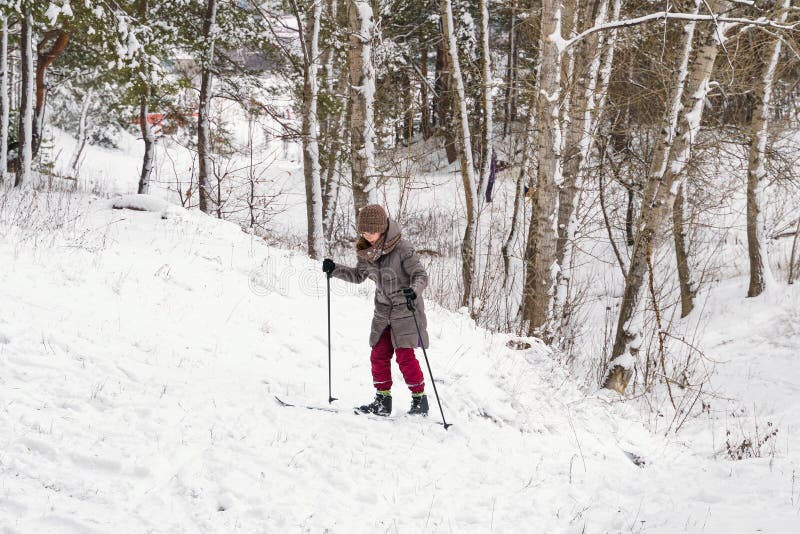 Niña esquiando cuesta arriba en el bosque invernal imagen de archivo Niña esquiando cuesta arriba en el bosque invernal imagen de archivo