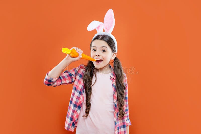 Niña feliz de Pascua que usa orejas para cacería de conejito en vacaciones de Pascua cazando conejitos de zanahoria imagen de archivo libre de regalías