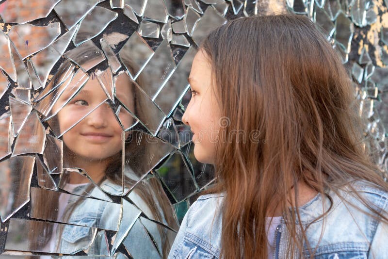 Young girl looks in a broken mirror and smiles on a mirror. Young girl looks in a broken mirror and smiles on a mirror.