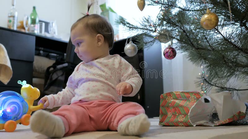 NiÃ±a linda abre regalos cerca del Ã¡rbol de Navidad