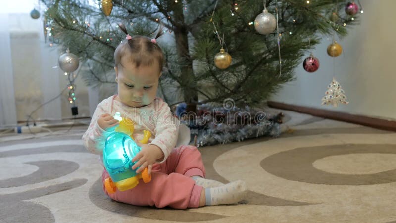 NiÃ±a linda abre regalos cerca del Ã¡rbol de Navidad