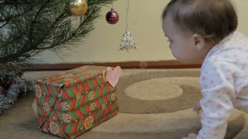 NiÃ±a linda abre regalos cerca del Ã¡rbol de Navidad