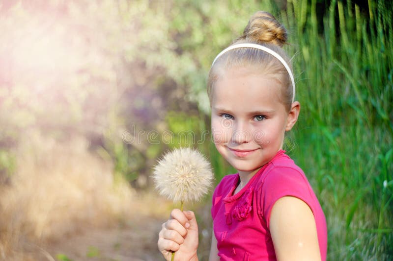 Niña linda con el diente de león en el prado adentro imagen de archivo Niña linda con el diente de león en el prado adentro imagen de archivo