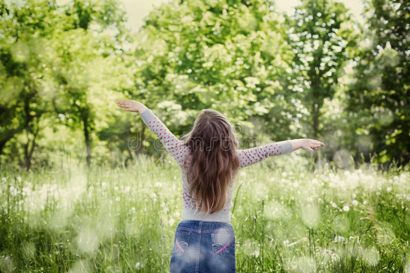 Niña linda con las manos aumentadas en el aire que se opone a la naturaleza mágica en día soleado fotos de archivo libres de regalías Niña linda con las manos aumentadas en el aire que se opone a la naturaleza mágica en día soleado fotos de archivo libres de regalías