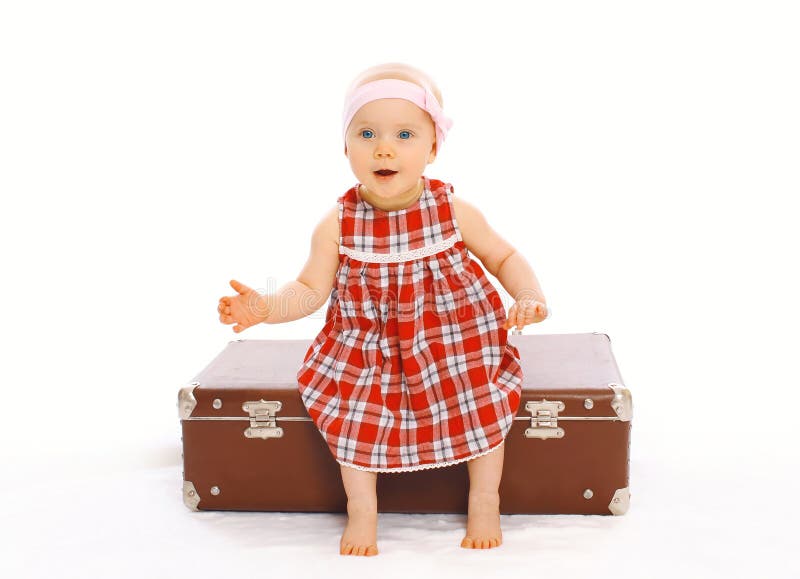 Niña linda del niño en el vestido que se sienta en jugar de la maleta fotografía de archivo libre de regalías Niña linda del niño en el vestido que se sienta en jugar de la maleta fotografía de archivo libre de regalías