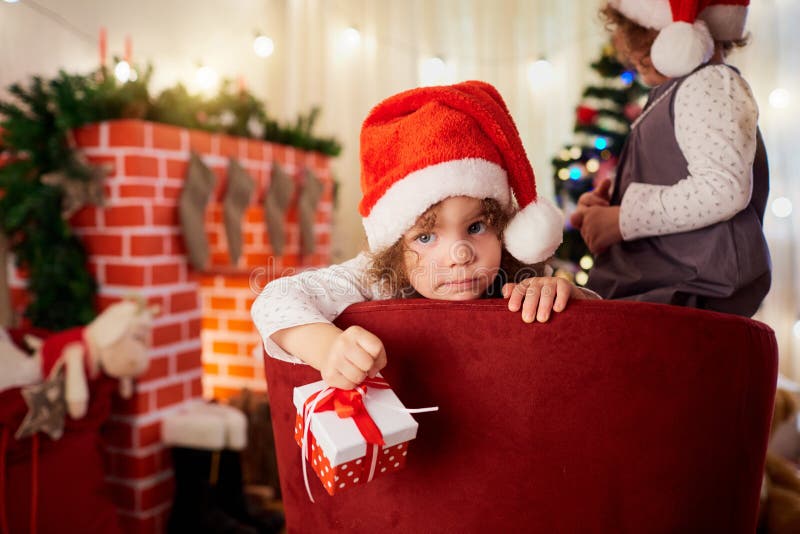 Niña linda en el sombrero de Santa Claus con un regalo a disposición l foto de archivo Niña linda en el sombrero de Santa Claus con un regalo a disposición l foto de archivo