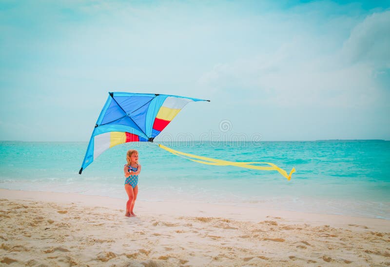 Niña linda feliz que vuela una cometa en la playa imágenes de archivo libres de regalías Niña linda feliz que vuela una cometa en la playa imágenes de archivo libres de regalías