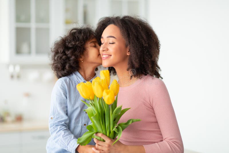Niña negra celebrando el día de las madres saludando a mamá con flores