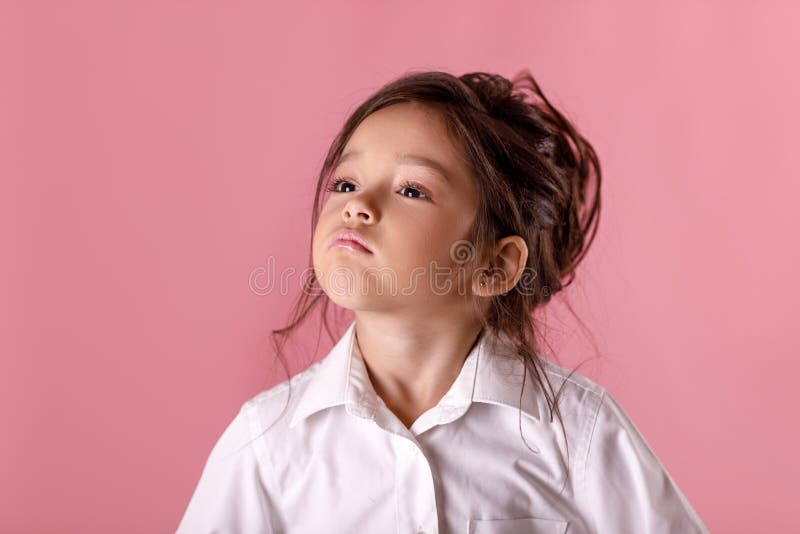 Niña orgullosa linda en la camisa blanca en fondo rosado Emociones humanas y expresión facial foto de archivo libre de regalías