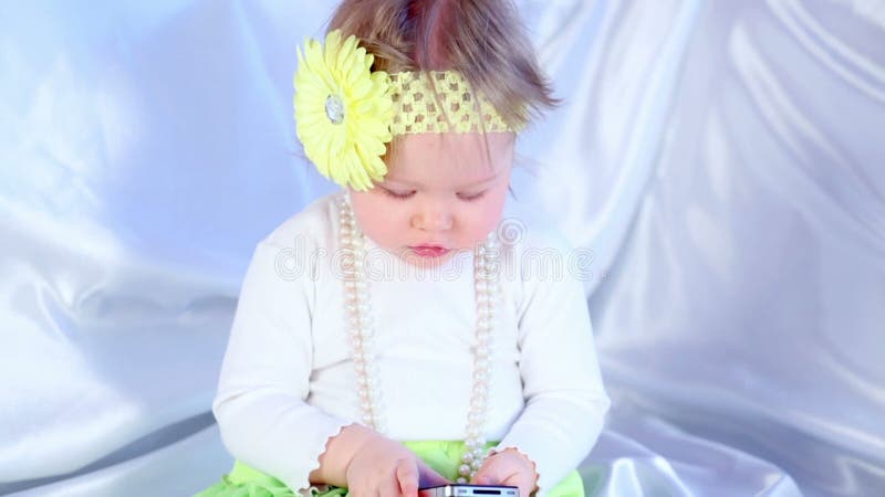 Niña pequeña de suéter blanco con banda de cabeza de flor almacen de metraje de vídeo