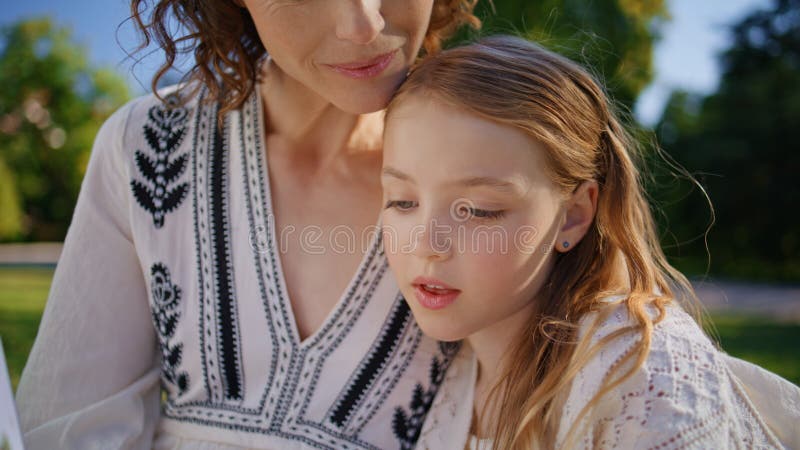 Niña pequeña leyendo cuento de hadas para mamá en el acogedor armario del parque. reposo femenino imagenes de archivo