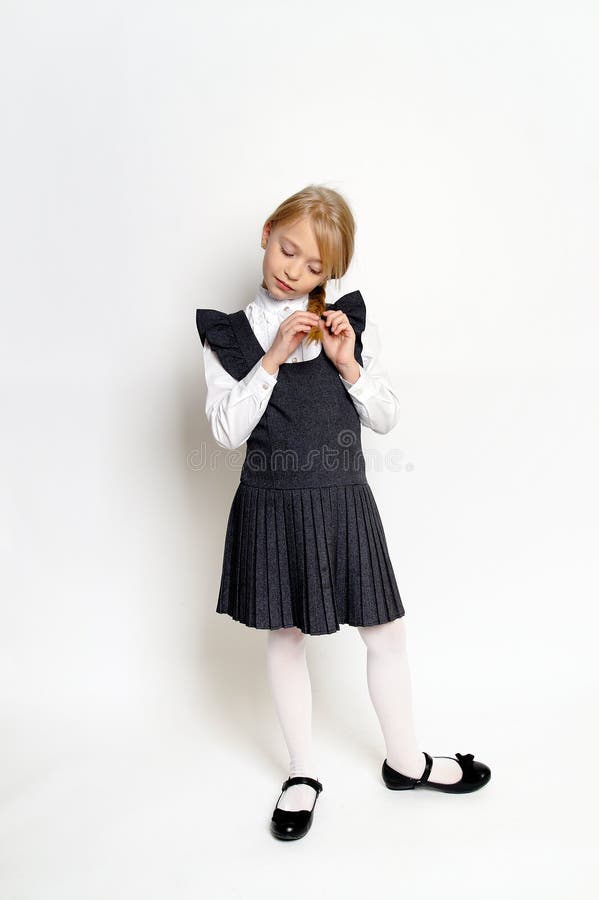 Niña pequeña posando con uniforme escolar imagen de archivo