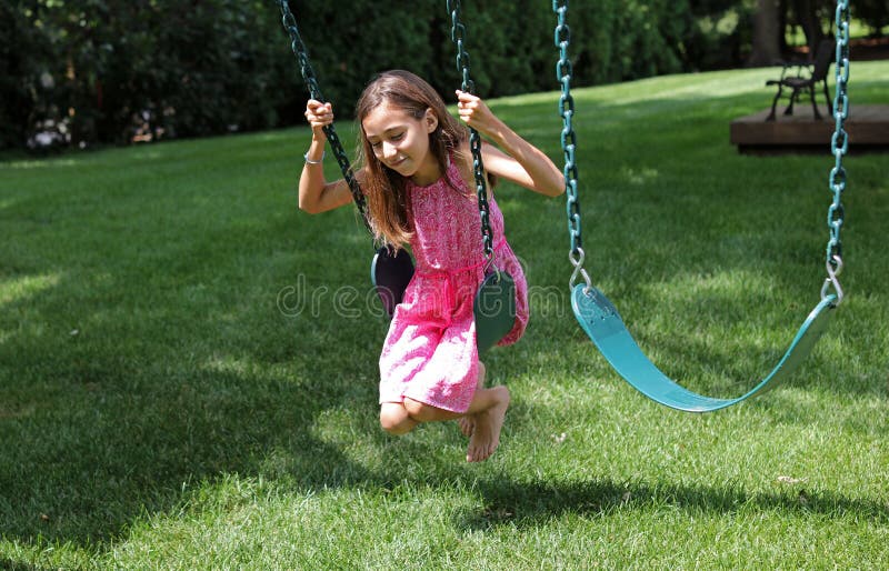 Niña preciosa en los oscilaciones en el parque con el vestido rosado durante verano en Michigan fotografía de archivo libre de regalías Niña preciosa en los oscilaciones en el parque con el vestido rosado durante verano en Michigan fotografía de archivo libre de regalías