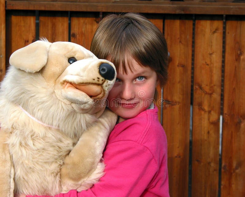 Niña que abraza un perro de juguete grande de la felpa imagen de archivo libre de regalías Niña que abraza un perro de juguete grande de la felpa imagen de archivo libre de regalías