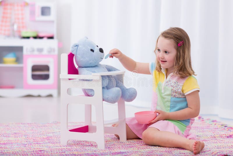 Niña pequeña alimentando a su oso de peluche fotografía de archivo