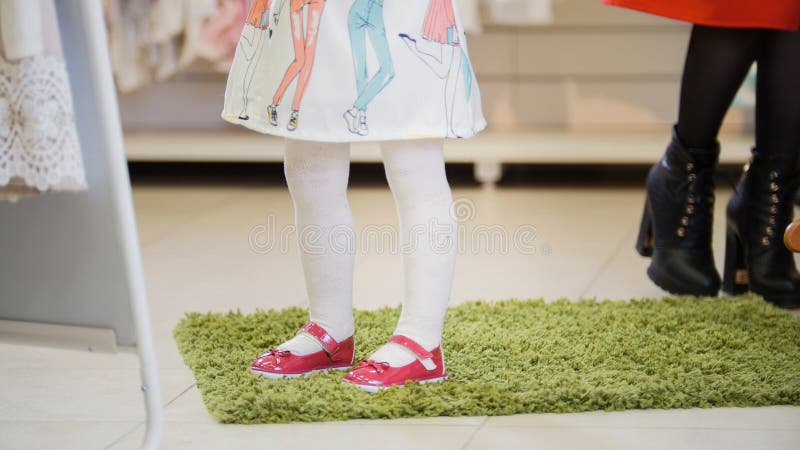 Niña que intenta en los zapatos rosados en la tienda para los niños foto de archivo libre de regalías Niña que intenta en los zapatos rosados en la tienda para los niños foto de archivo libre de regalías