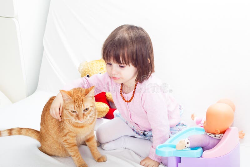 Little girl playing with cat and baby dolls. Little girl playing with cat and baby dolls