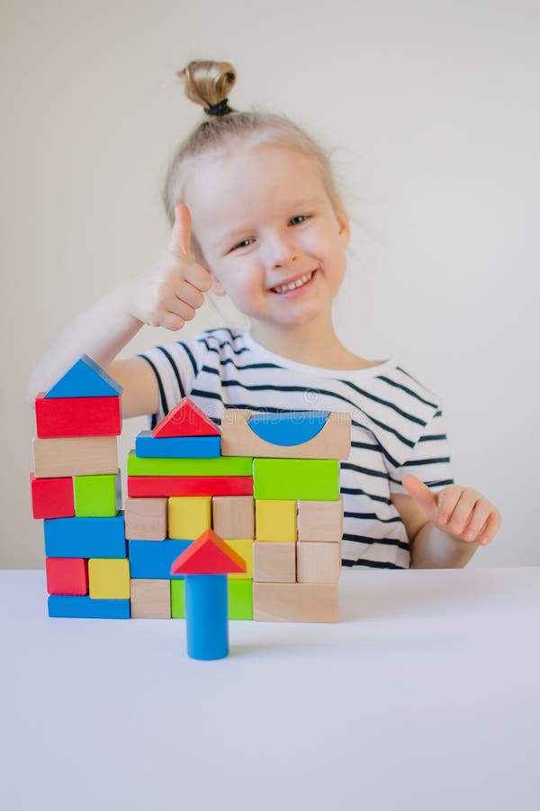 Niña que juega con los cubos coloridos de madera en casa imagen de archivo libre de regalías Niña que juega con los cubos coloridos de madera en casa imagen de archivo libre de regalías
