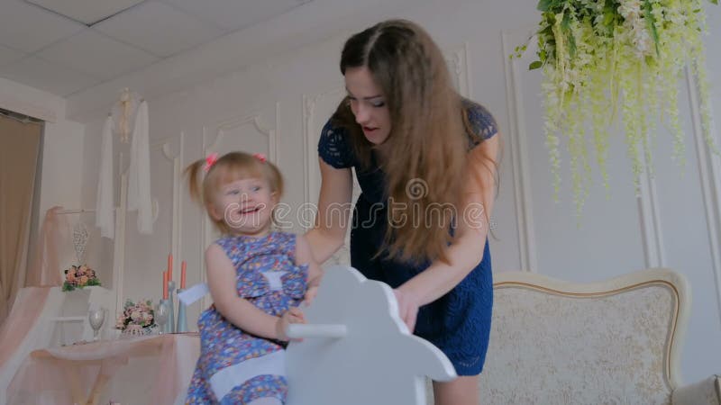 Niña que juega en caballo mecedora de madera