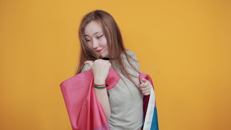 Niña que muestra el pulgar a un lado, usando ropa casual cubierta de bandera bisexual