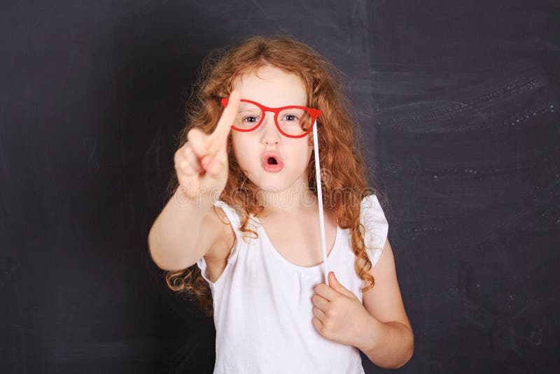 School girl showing shaking finger saying no, near blackboard. School girl showing shaking finger saying no, near blackboard.