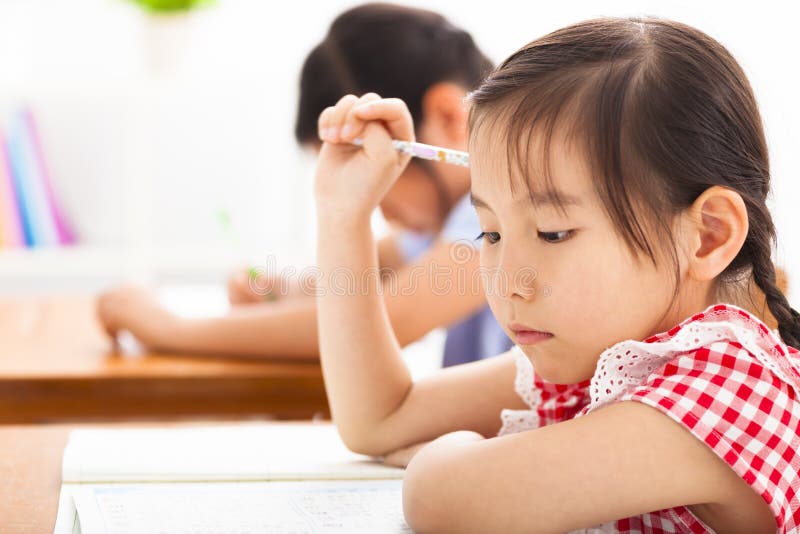 Niña que piensa en la sala de clase imagen de archivo libre de regalías Niña que piensa en la sala de clase imagen de archivo libre de regalías