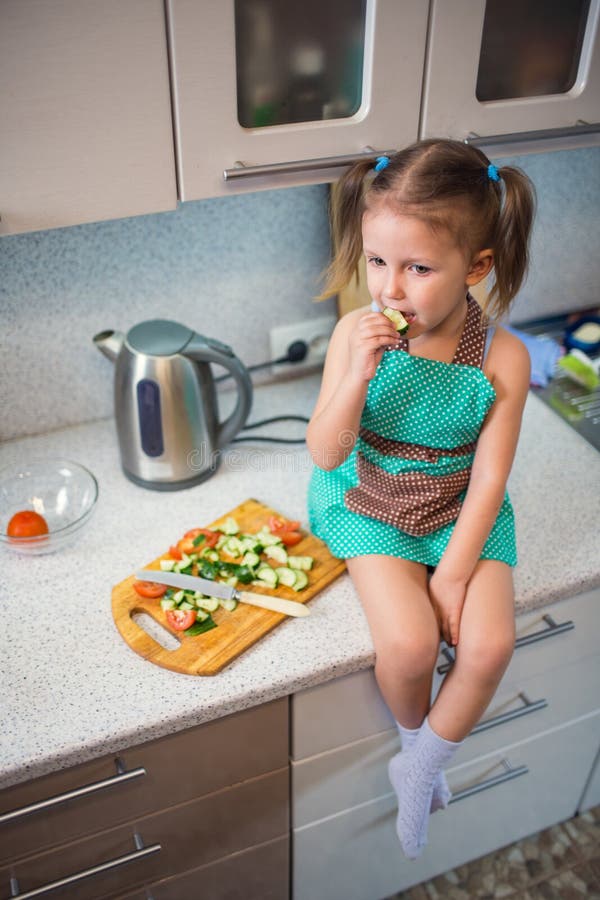 Niña que prepara la ensalada en la cocina imagenes de archivo Niña que prepara la ensalada en la cocina imagenes de archivo