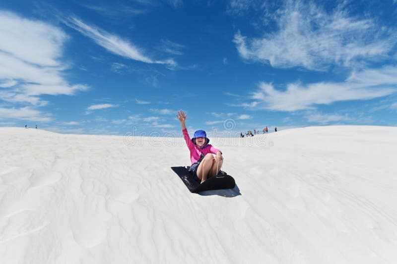 Niña que se desliza por las dunas de arena de Lancelin en el oeste de Australia imagenes de archivo