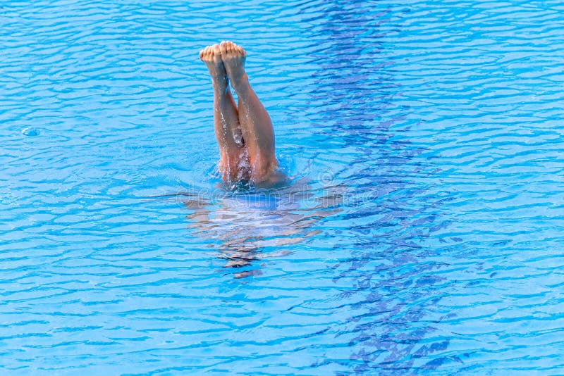 Synchronised Swimming girl underwater feet legs out dance style in pool with surface wind blue water ripples texture. Synchronised Swimming girl underwater feet legs out dance style in pool with surface wind blue water ripples texture