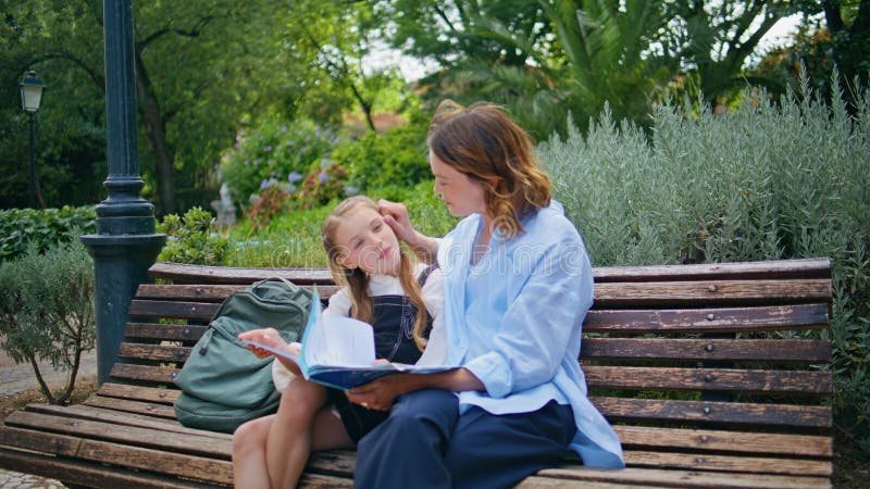 Niña voltea páginas leyendo cuento de hadas abrazándose en el jardín de la ciudad foto de archivo