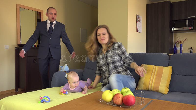 Niñera puesta en el sofá cerca de bebé Hombre enojado del padre en traje 4K