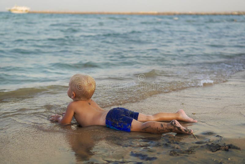Niñito con el pelo rubio divirtiéndose en la playa fotos de archivo libres de regalías