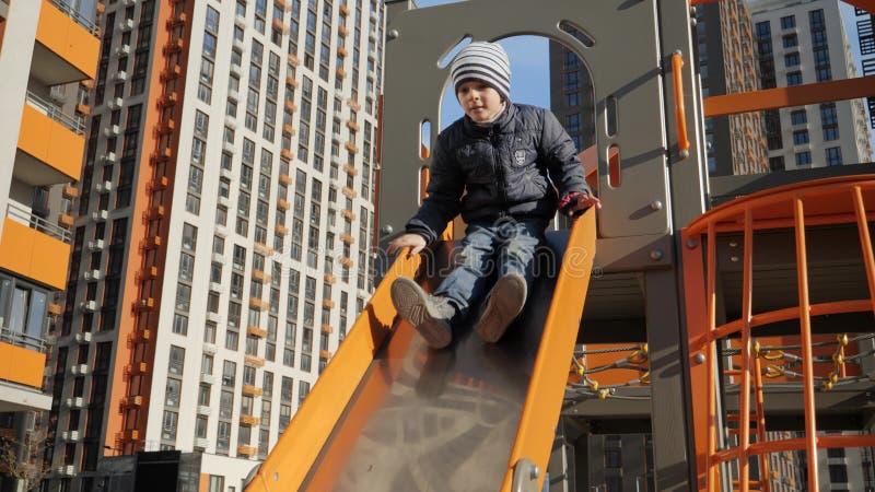 Niñito en el tobogán de metal en el patio de la casa. el concepto de deportes de desarrollo infantil y