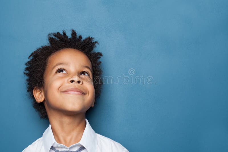 Little black child boy smiling and looking up on blue background. Little black child boy smiling and looking up on blue background.