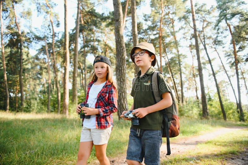Niñito y niña van de excursión por el camino del bosque fotografía de archivo