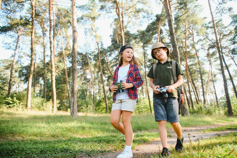 Niñito y niña van de excursión por el camino del bosque foto de archivo