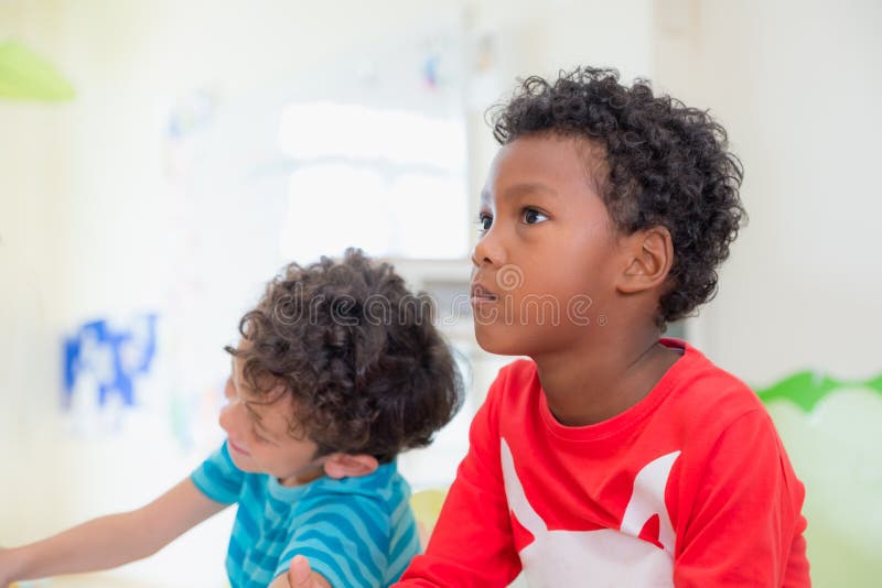 Niño afroamericano de la pertenencia étnica con la emoción cambiante que se sienta en el cla foto de archivo Niño afroamericano de la pertenencia étnica con la emoción cambiante que se sienta en el cla foto de archivo