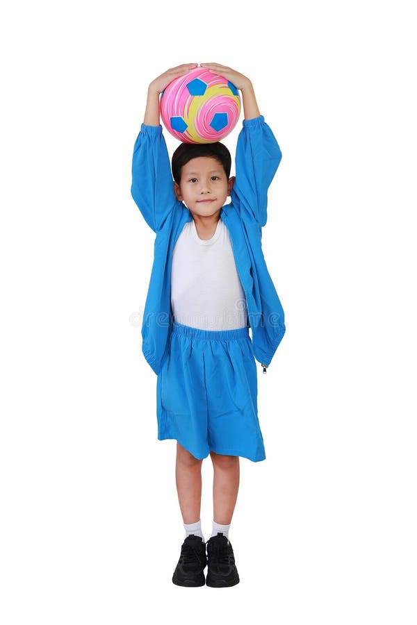 Niño asiático con ropa de cabeza de capucha azul o ropa deportiva de pie y sosteniendo el fútbol aislado de fondo blanco. Imagen c foto de archivo libre de regalías