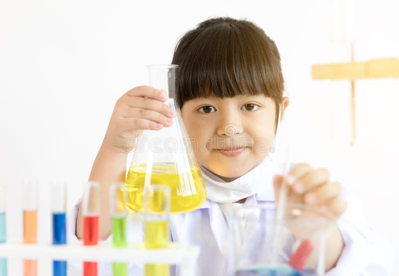Niño asiático que juega al científico con los tubos coloridos del laboratorio